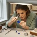 Palaghia Nicolaysen, gemologist, examining a sapphire under a jeweller's loupe at a Cardiff workbench